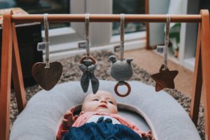 2nd baby must haves, baby laying under a wooden play gym